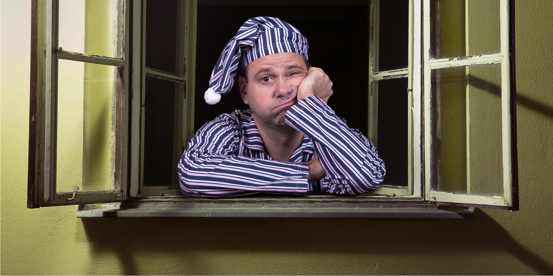 אדם הסובל מנדודי שינה מביט החוצה מחלון ביתו